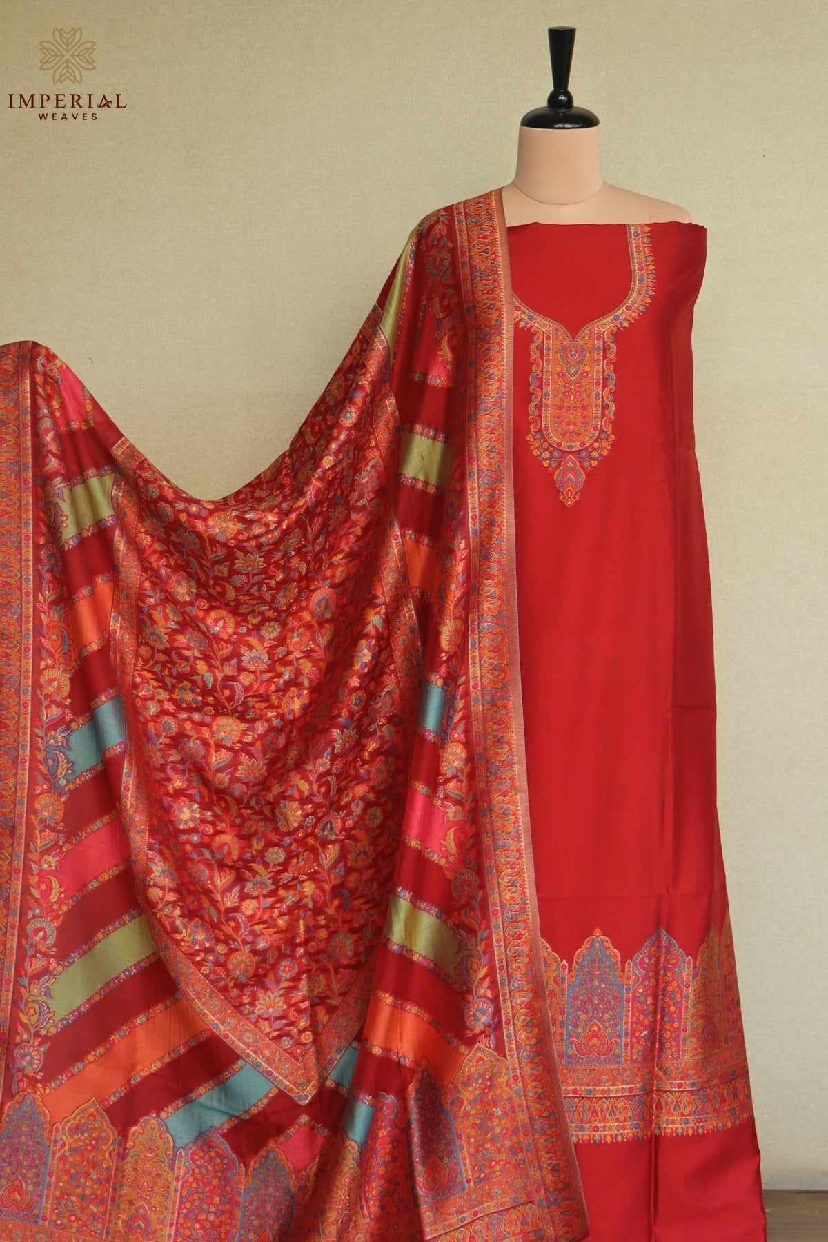 A red ethnic suit set featuring a red kurta with ornate gold and thread weaving, a matching red dupatta with intricate floral patterns and striped borders, and a coordinating red and gold silk shawl 