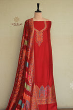 A red traditional Indian salwar kameez suit displayed on a mannequin, featuring a solid red kurta with ornate gold and multicolor embroidery, a matching red dupatta with detailed gold and multicolor patterns, 